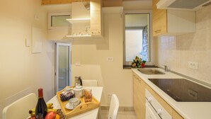 A compact kitchen with a wooden ceiling, a built-in stove, a sink, and a dining area with a tray of breakfast items. - 2 bedroom gorgeous apartment in Monte Isola (Monte Isola)