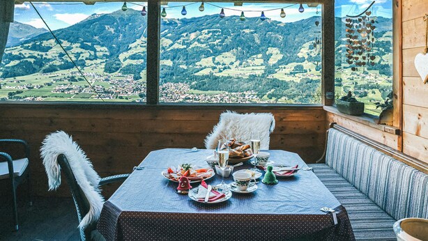 Un coin repas avec une table préparée pour le thé, donnant sur un paysage montagneux.