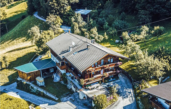Un grand chalet en bois doté de nombreux balcons et d’un vaste patio entouré d’une végétation luxuriante.