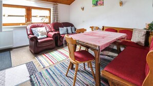 Un salon chaleureux avec un canapé en cuir rouge, une table à manger en bois et un tapis rayé aux couleurs vives.