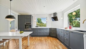 Eine moderne Küche mit dunklen Schränken, einer weißen Arbeitsplatte und Holzboden.