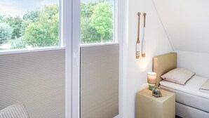 A bedroom with a large window, a bedside table with a lamp, and a view of greenery outside. - Stunning home in Büsum with sauna (Büsum)