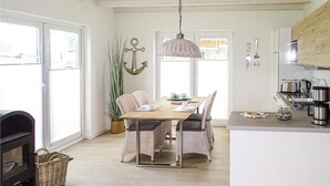 A cozy kitchen with a wooden table, chairs, a hanging light fixture, and a potted plant. - Stunning home in Büsum with sauna (Büsum)
