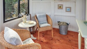 Una habitación acogedora con sillas de mimbre, una mesita y vistas por la ventana.