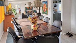 Un comedor con una mesa de madera, sillas negras y un jarrón con flores secas.