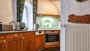 A kitchen with wooden cabinets, a built-in oven, and a coffee maker. - Ferienhaus Lausche Haeusl (Waltersdorf)