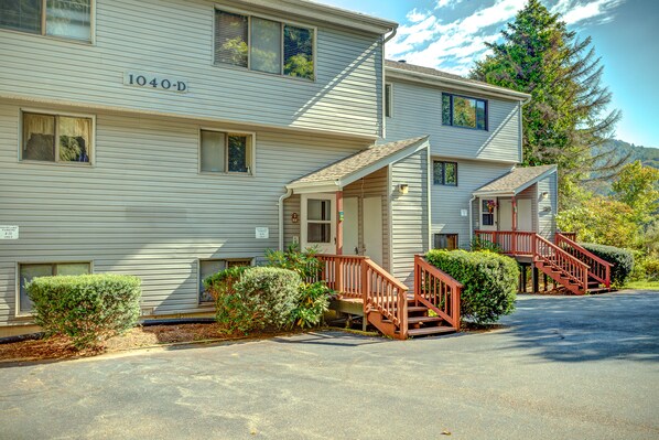 A two-story building with a number '1040-D' on the side, a front porch with a wooden railing, and a driveway leading to the entrance. - Walk to Ski/Tennis Mountain Condo with Golf Course View (Sugar Mountain)