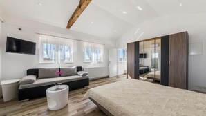 Een moderne slaapkamer met een groot bed, een bank, een televisie en een spiegel.