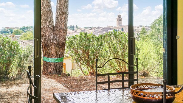 A room with a view of a tree, a chair, and a table with a bowl. - Beautiful home in Caux (Caux)