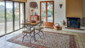 A dining area with a table and chairs, a fireplace, and a view through large glass doors. - Beautiful home in Caux (Caux)