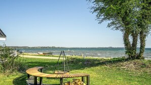 A wooden swing set and a fire pit in a grassy area with a view of the sea. - Beach front home in Sjølund (Sjølund)