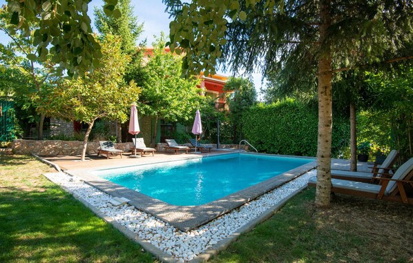 A rectangular swimming pool with a stone border, surrounded by a grassy area and trees. - 4 bedroom gorgeous home in Grubine (Grubine)