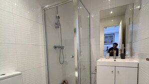 Un baño moderno con ducha envuelta en vidrio, inodoro blanco y tocador con espejo.