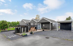 Une maison moderne à deux étages, dotée d’un garage fermé et d’un petit espace extérieur aménagé pour se détendre.