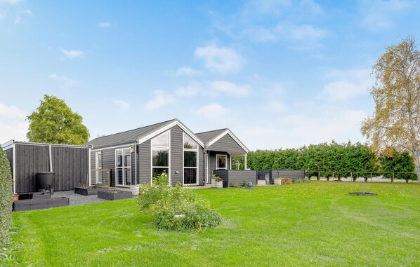 Une maison moderne dotée d’un grand jardin devant et d’un garage indépendant.