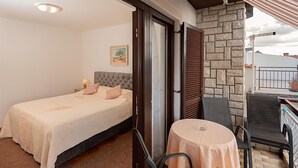 A bedroom with a bed, a small table, and a view of the outside. - 2 bedroom nice apartment in Jadranovo (Jadranovo)