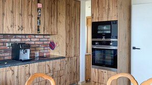 Eine Küche mit Holzausstattung, einer Kaffeemaschine und einem Einbauofen.