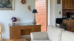 Ein Wohnzimmer mit einem Holztisch, einem Globus, einer Lampe, einer Couch und einer Ziegelwand.