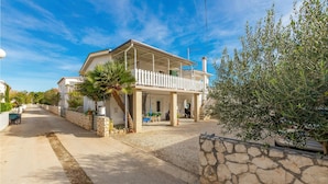 Una casa costera con balcón, paredes de piedra y cielo despejado.
