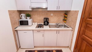 A compact kitchen with white cabinets, a microwave, a coffee maker, and a sink. - 1 bedroom amazing apartment in Podstrana (Podstrana)