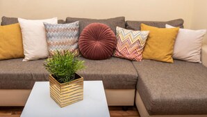 A sectional sofa with various patterned cushions and a small potted plant on a white table. - 1 bedroom amazing apartment in Podstrana (Podstrana)