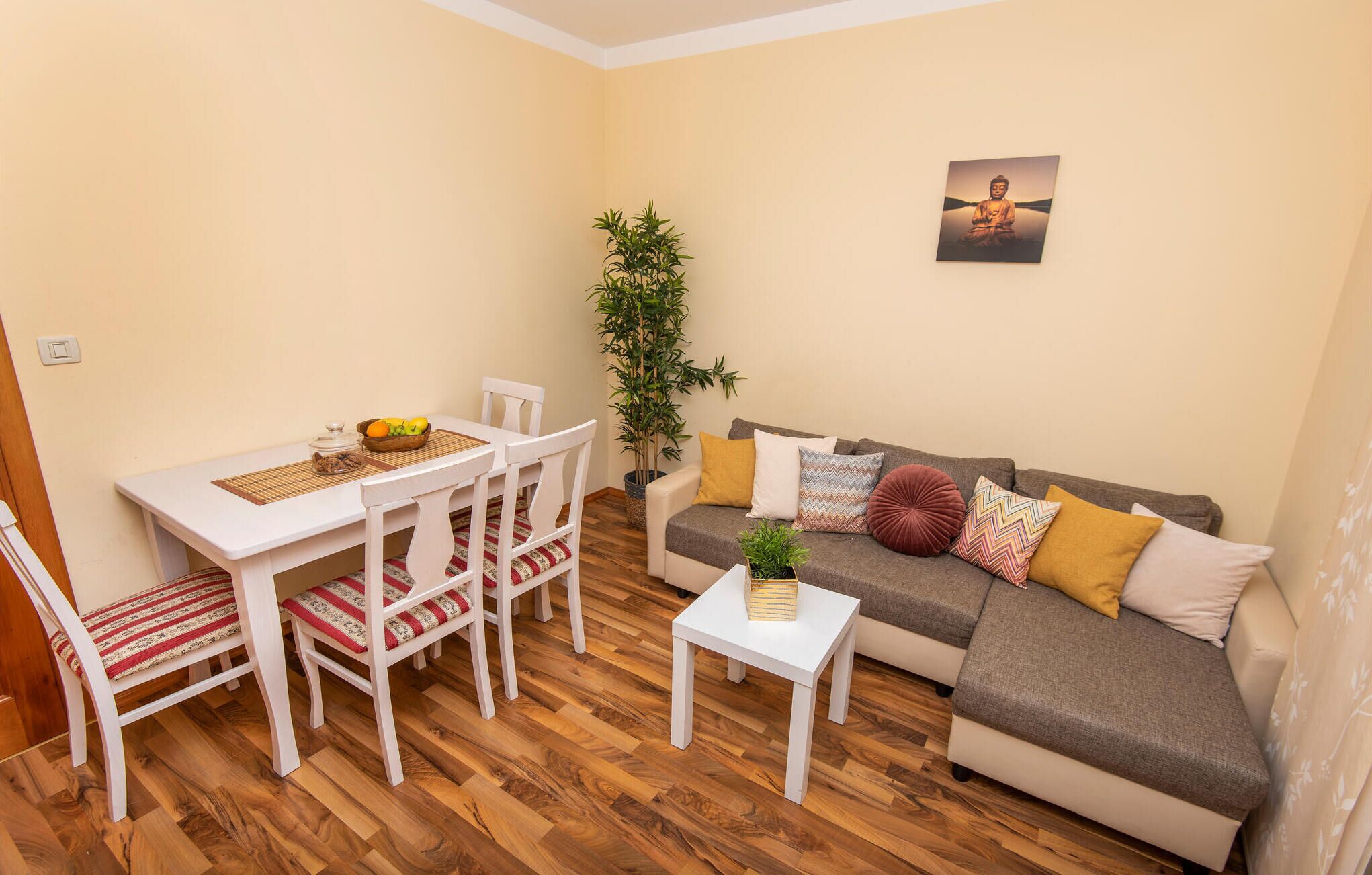 A cozy living room with a dining table, chairs, a sofa, and a small white table.