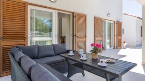 An outdoor seating area with a sofa, table, and chairs, featuring wooden shutters and a glass door leading to a balcony. - Gorgeous home in Labin (Labin)