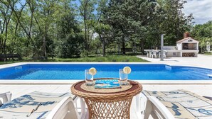 A swimming pool with a wicker table in the foreground, surrounded by white chairs. - Gorgeous home in Labin (Labin)