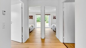 A hallway with two beds, a ceiling with recessed lighting, and a view of the outdoors through large windows.