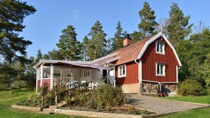 Ein rotes Holzhaus mit einer Veranda und einem Kiesweg.