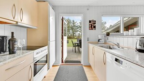 Una cocina moderna con armarios blancos, un lavavajillas Bosch y vistas al exterior.