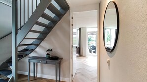 A modern interior with a spiral staircase, a small table with a plant, and a large mirror on the wall. - Nice home in Vlagtwedde (Vlagtwedde)