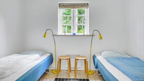 A small, clean room with two single beds, a window with a view of greenery, and a table with two stools. - 3 bedroom nice home in Læsø (Læsø)