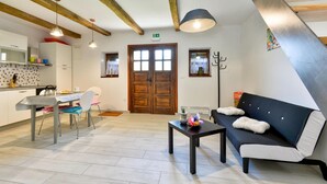 A modern kitchen with a dining area, a sofa, and a table with a vase. - Nice home in Breznicki Hum with WiFi (Breznicki Hum)