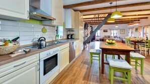 A spacious kitchen with a Bosch oven, wooden flooring, and a dining area with green chairs and a wooden table. - Nice home in Breznicki Hum with WiFi (Breznicki Hum)