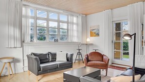 A modern living room with a grey leather sofa, a brown leather armchair, and a black coffee table. There is a large window with white curtains, a floor lamp, and a painting on the wall. - 4 bedroom stunning home in Torrig L (Torrig L)