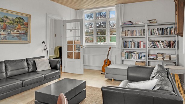 A living room with a black leather sofa, a grey armchair, a coffee table, a bookshelf, and a guitar leaning against the wall. - 4 bedroom stunning home in Torrig L (Torrig L)