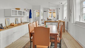 A modern kitchen with white cabinetry, a wooden countertop, and a dining area with a wooden table and leather chairs. - 4 bedroom stunning home in Torrig L (Torrig L)