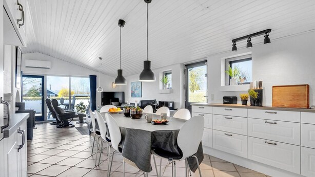A modern kitchen with white cabinetry, a dining area with a marble table, and a view of the outdoors. - Amazing home in Juelsminde with sauna (Juelsminde)