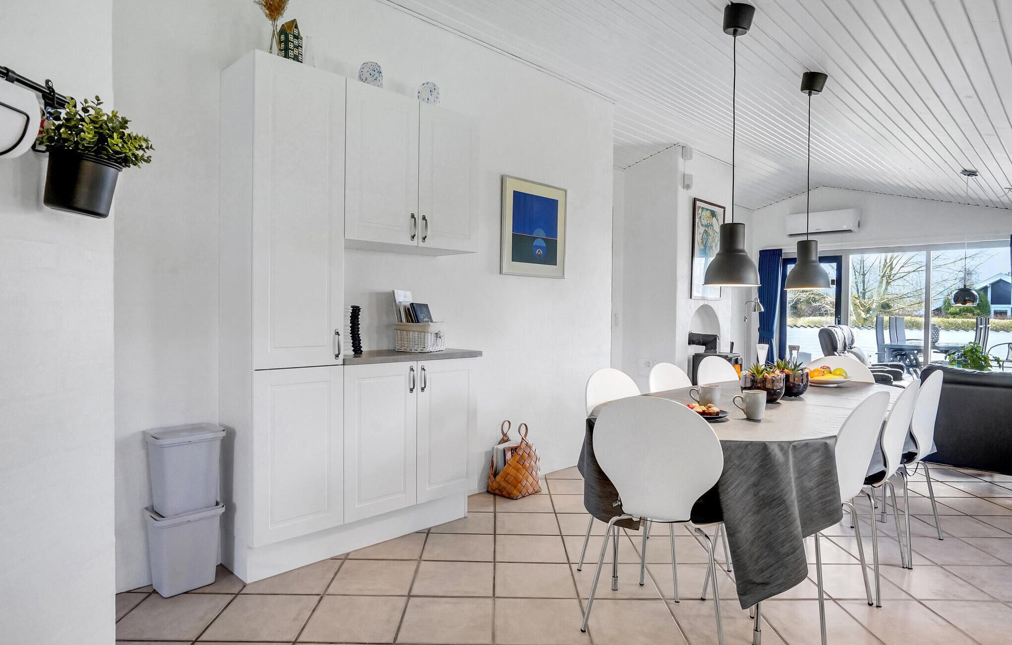 Une cuisine moderne avec des meubles blancs, un coin repas doté d’une table ronde et de chaises, et une vue sur l’extérieur.