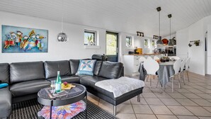 A modern living room with a black leather sofa, a round coffee table with a colorful rug, and a painting on the wall. - Amazing home in Juelsminde with sauna (Juelsminde)