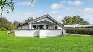 A single-story house with a sloped roof, a covered porch, and a well-maintained lawn. - Amazing home in Juelsminde with sauna (Juelsminde)