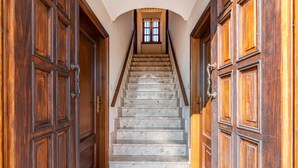 Un escalier bordé de portes en bois de chaque côté, menant à un palier doté d’une fenêtre.