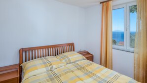 Un dormitorio con cama, cabecera de madera y ventana con cortinas.