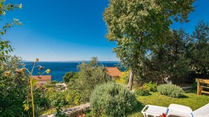 Un jardín con vista al mar, mobiliario exterior y una variedad de plantas.