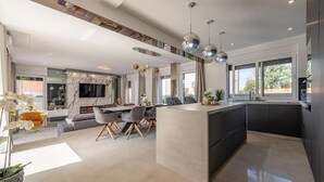 A modern kitchen with a central island, a dining area with a sofa and chairs, and a living area with a TV and seating. - Awesome home in Zaton (Zaton)