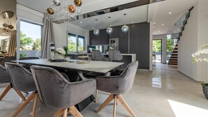 A modern dining area with a large table, grey upholstered chairs, and a chandelier. - Awesome home in Zaton (Zaton)
