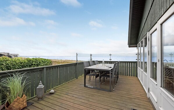 A wooden deck with a table and chairs, overlooking a body of water.