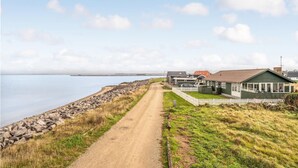 Une route côtière qui mène à une rangée de maisons offrant une vue sur la mer.