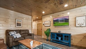 Une pièce chaleureuse avec des murs en bois, un canapé en cuir marron, une table basse en bois et un meuble bleu.
